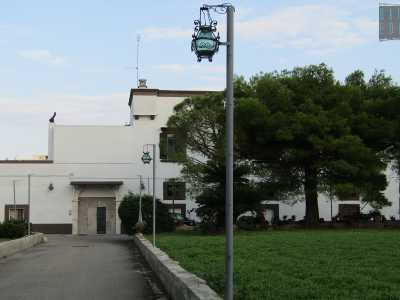 Quello che riusciamo a vedere attraverso il cancello � un edificio che si sviluppa su due piani, a base rettangolare e bianco, arricchito solo con fasce monocrome marroni
